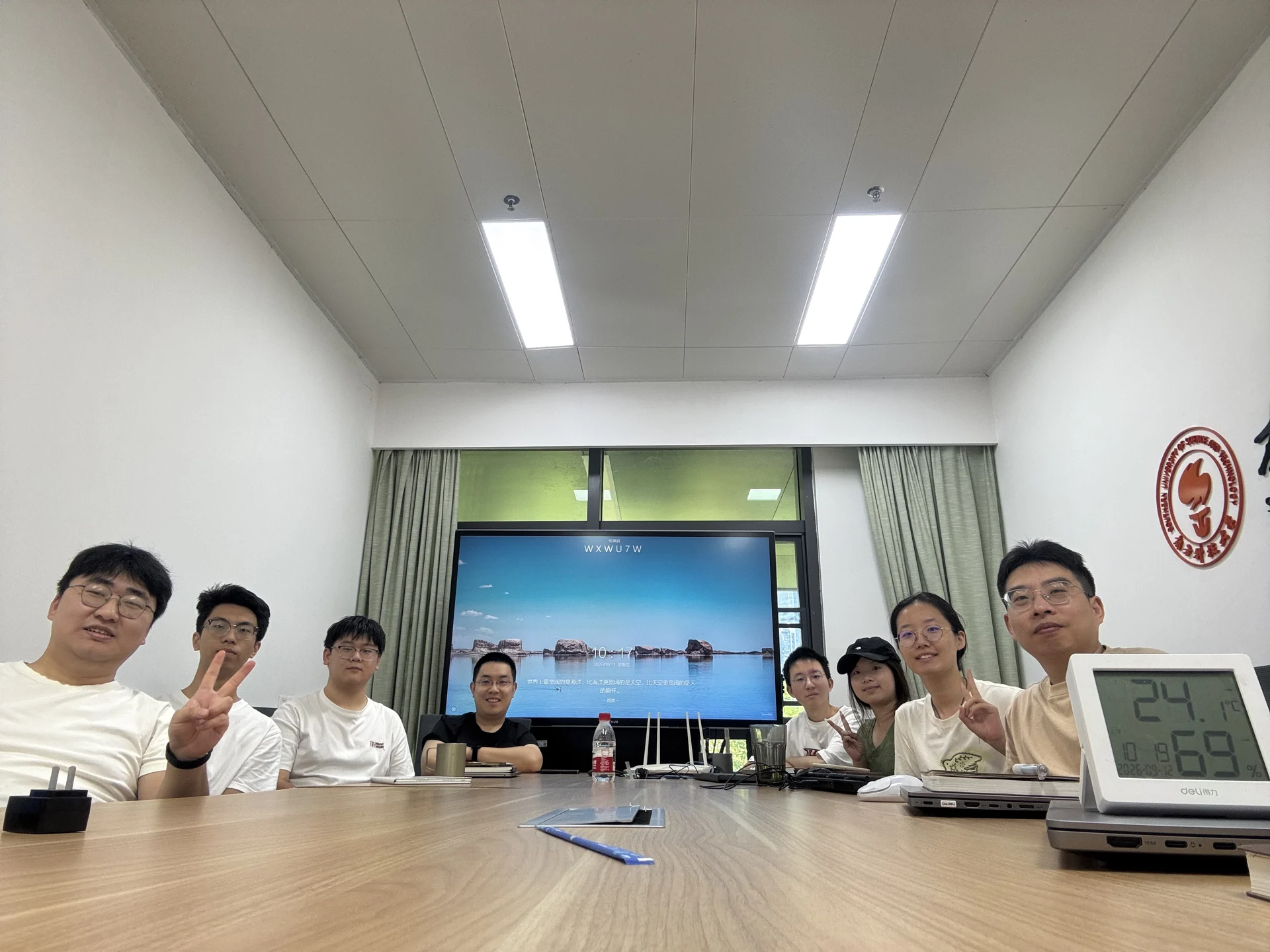 Group members gathered around a meeting table with a presentation screen behind them.
